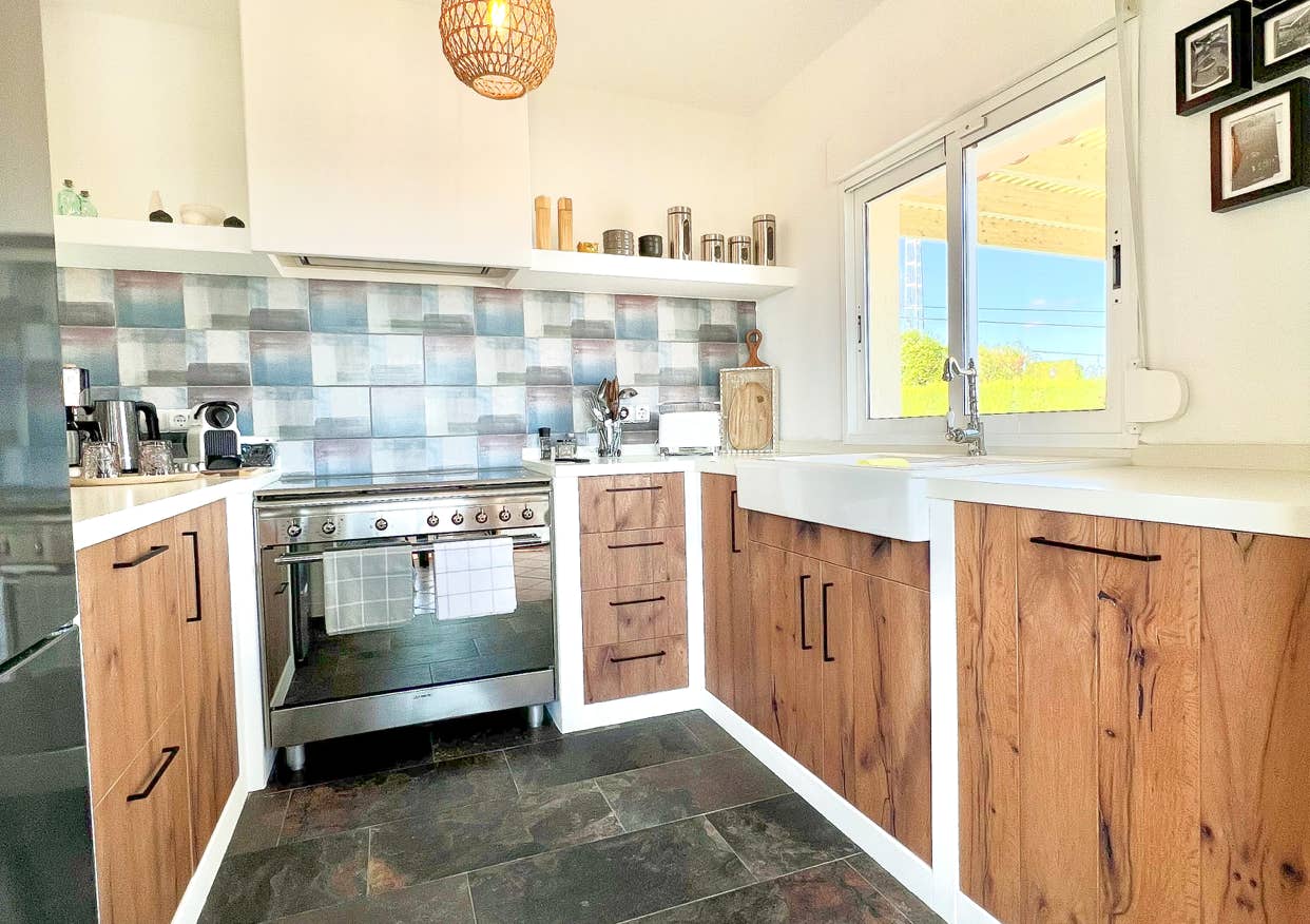Kitchen with wooden fronts, ceramic tiles, and modern equipment – project in Denia/Montgó.