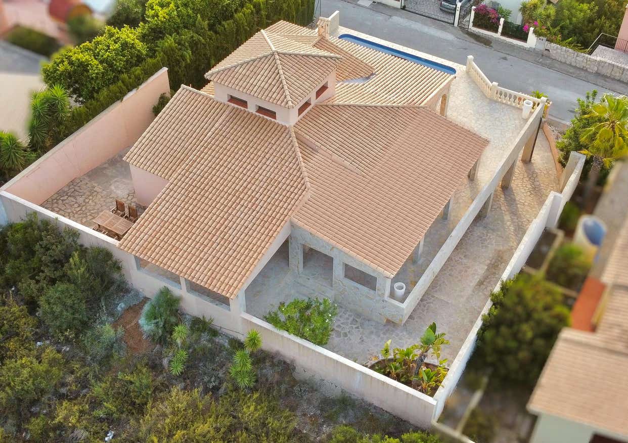 Vogelperspektive auf eine helle Satteldachvilla mit Gartenanlage und Pool