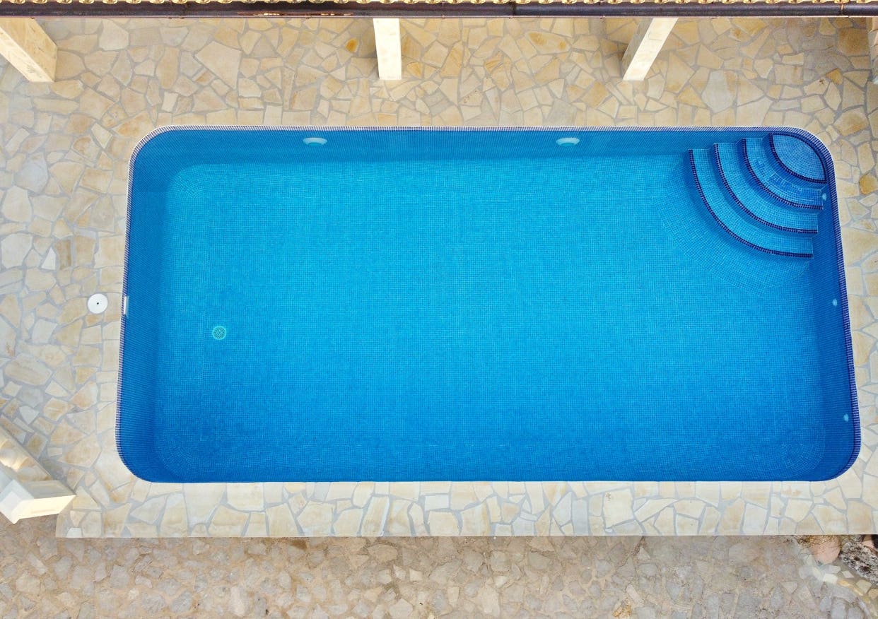 Luftbildaufnahme eines rechteckigen Pools mit Natursteinumrandung