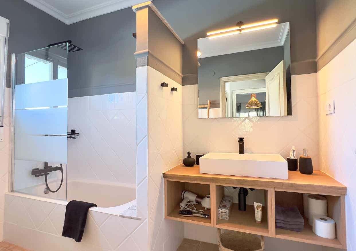 Modern bathroom with glass shower, wooden details, and stylish lighting.